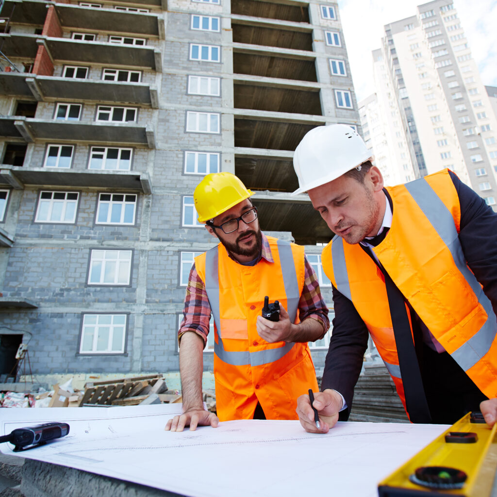 Modern engineer pointing at sketch in blueprint while explaining it to colleague