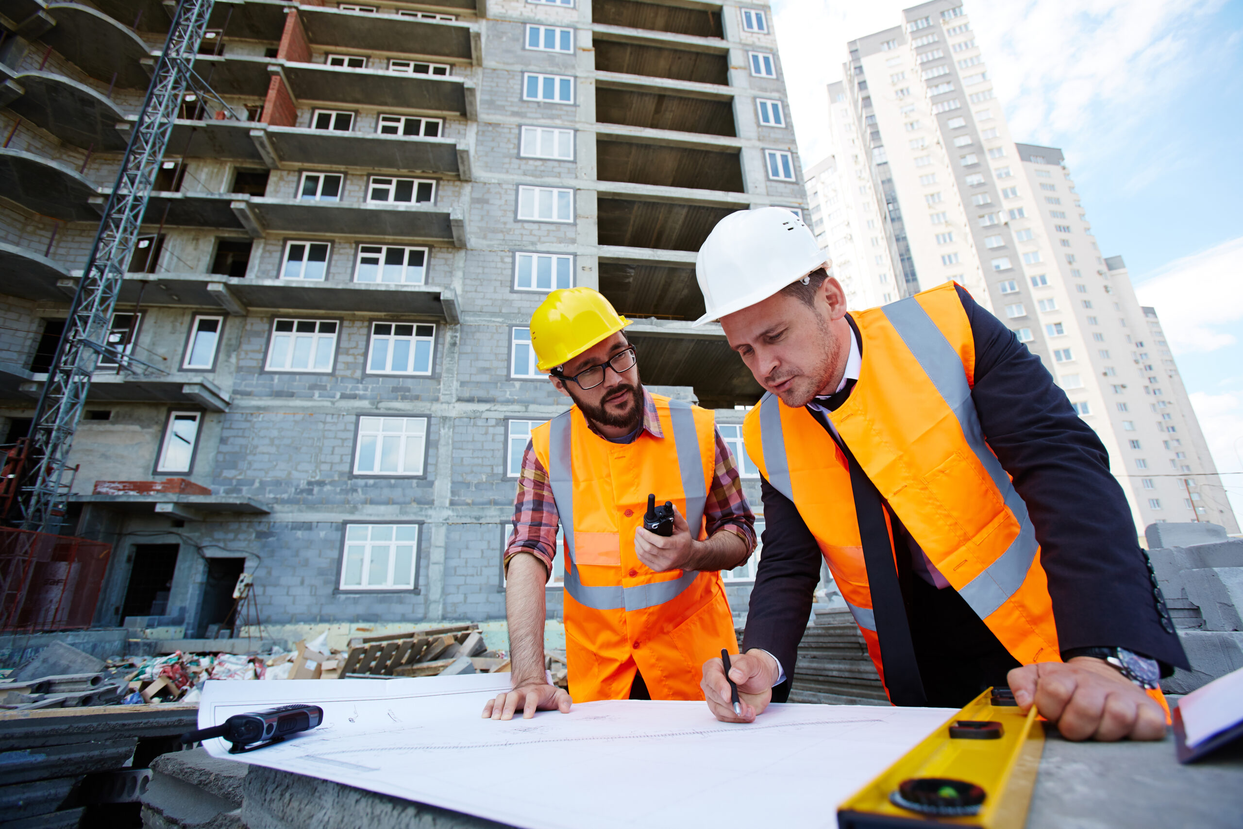 Modern engineer pointing at sketch in blueprint while explaining it to colleague